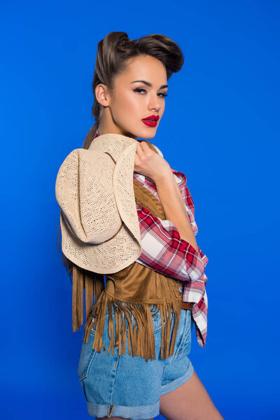 portrait of beautiful stylish woman with cowboy hat posing isolated on blue