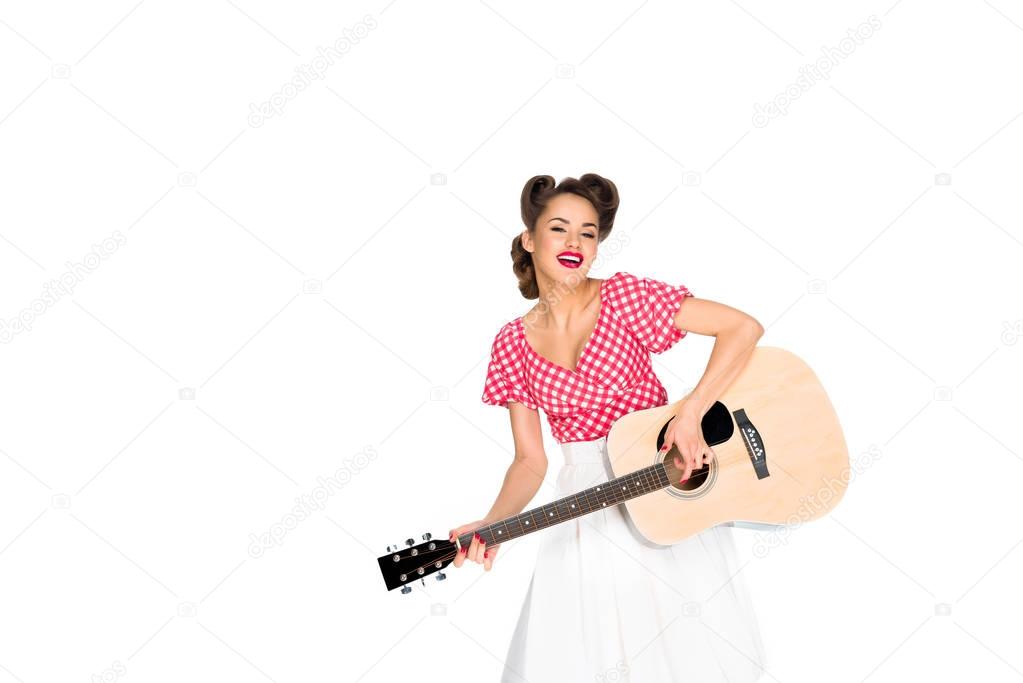 portrait of cheerful woman in pin up clothing playing guitar isolated on white