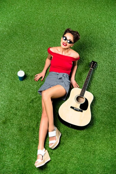 美丽的妇女的顶上的看法以吉他休息在绿色草坪 — 图库照片