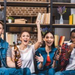 Emotionale junge multiethnische Freunde, die gemeinsam Bier trinken und Fernsehen schauen