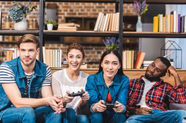 gülümseyen genç çok ırklı arkadaşlar joystick ile birlikte evde oynamak 