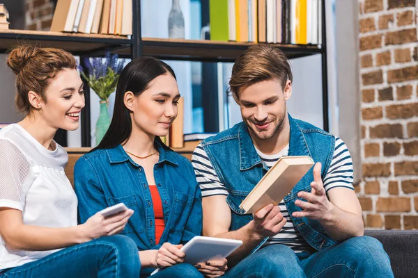 Smiling Young Man Showing Book Girls Using Digital Devices — Stock Photo, Image