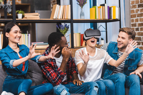 happy young friends having fun with virtual reality headset at home  