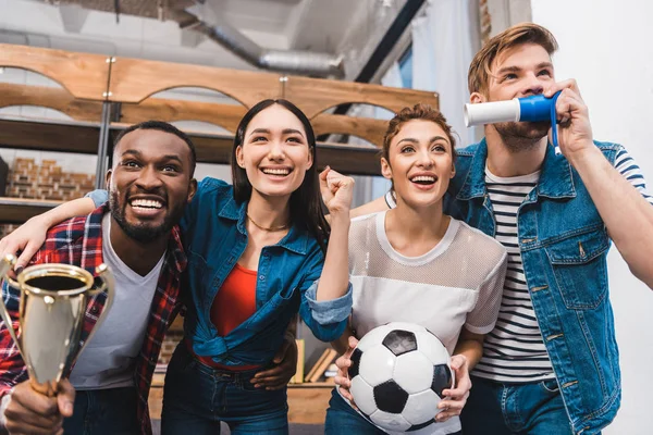 excited young multiethnic friends watching soccer match together at home
