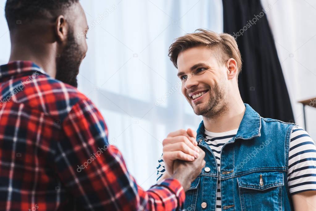 selective focus of young multiethnic men smiling each other 