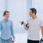 Femme d'affaires et son entraîneur personnel travaillant avec haltères au bureau