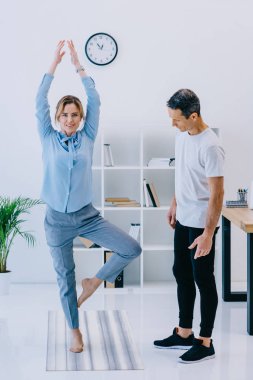 Onu eğitmen pratik Yoga ağacında işkadını poz ofiste