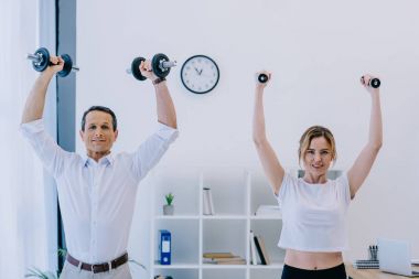 işadamı kadın onun kişisel antrenör ofiste dumbell ile çalışma dışarı ile
