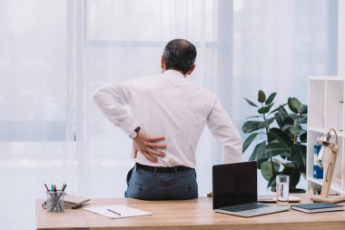 Dikiz ofisinde sırt ağrısı ile olgun iş adamı