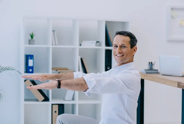 オフィスでのスクワットをやって幸せな成熟したビジネスマン — ストック写真