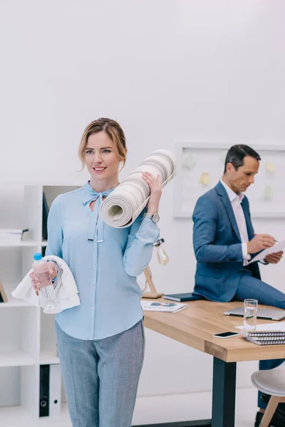 Geschäftsfrau Mit Fitnessgeräten Steht Modernen Büro Während Ihr Kollege Hintergrund — kostenloses Stockfoto