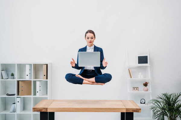 business woman using laptop while levitating in office
