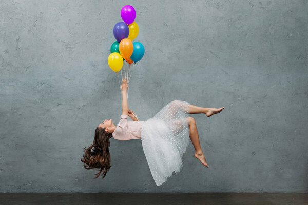 молодая женщина левитирует с красочными воздушными шарами
