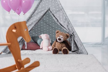 rocking horse with balloons and soft toys in room