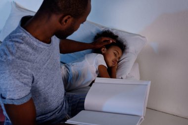 Afrikalı-Amerikalı babası holding kitap ve palming uyuyan kızı