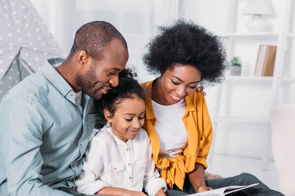 african american parents reading with daughter at home