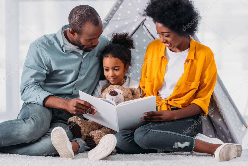 African american parents teaching daughter to read at home