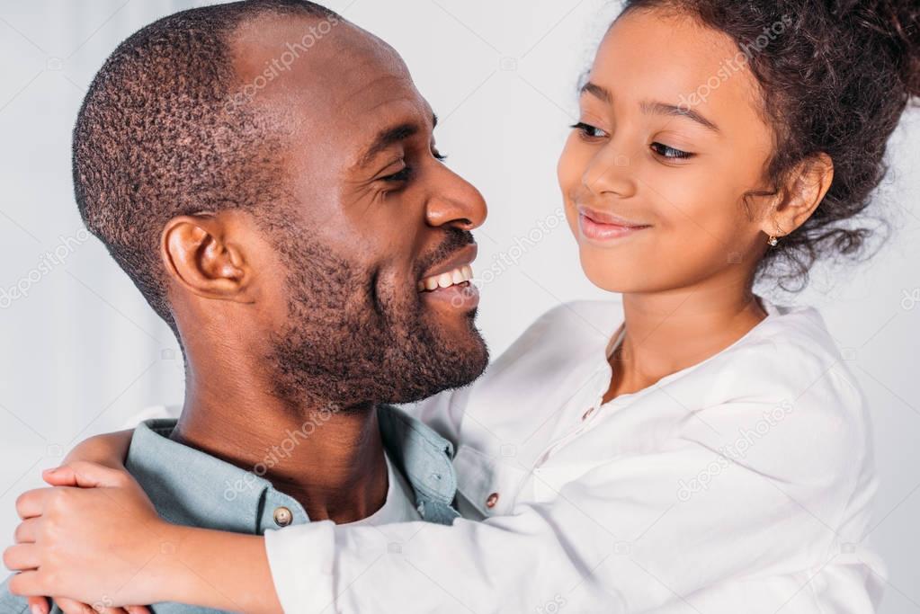 happy african american father and daughter looking at each other