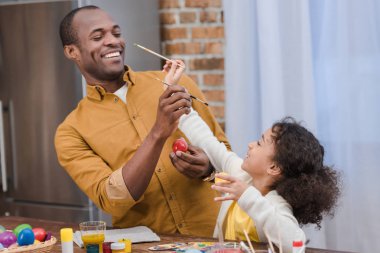 Afro-Amerikan baba ve kızı Paskalya yumurta boyama sırasında eğlenmek