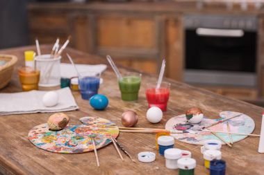 painted chicken eggs with paints and brushes on wooden table, easter concept clipart