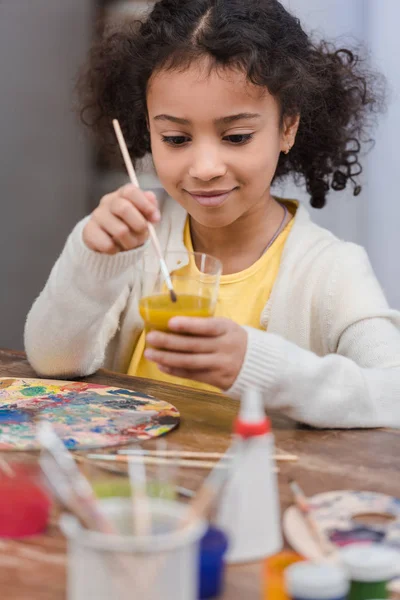 Criança Americana Africana Colocando Escova Vidro Com Tinta Para Pintar — Fotografia de Stock