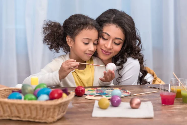 African American Mother Hugging Daughter While She Painting Easter Eggs — Stock Photo, Image