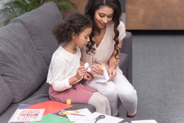 african american mother helping daughter to make greeting card on mothers day clipart