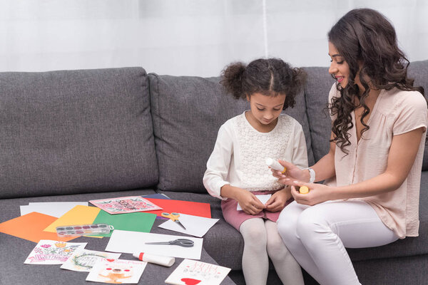 african american mother and daughter gluing paper for greeting card on mothers day