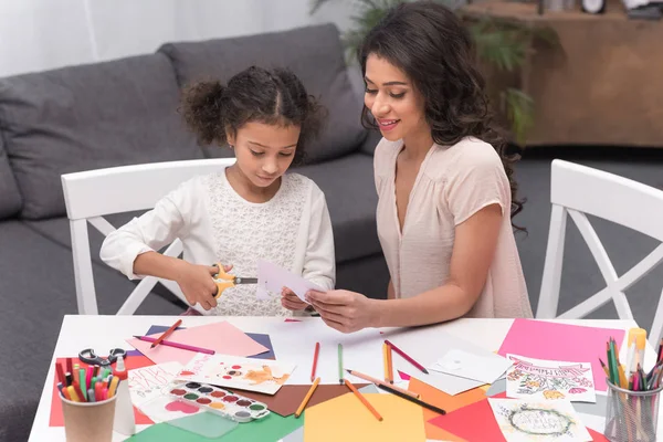 african american mother and daughter cutting paper for greeting card on mothers day