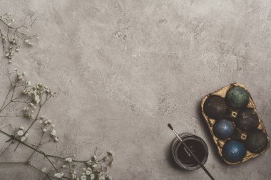 boyalı Paskalya yumurtaları içinde tepsi çiçekler, boya ve fırça ile üstten görünüm Beton üzerinde