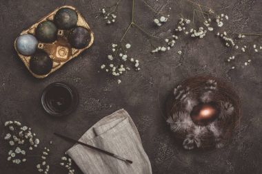 Üstten Görünüm geleneksel boyalı Paskalya yumurtaları içinde altın tepsi ve tepsi, boya ve fırça bez ve beton yüzeyinde