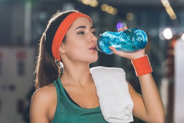sporty woman drinking water at gym clipart