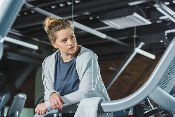 overweight woman leaning on rail of treadmill at gym