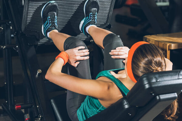 sporty woman training legs on training apparatus at gym 