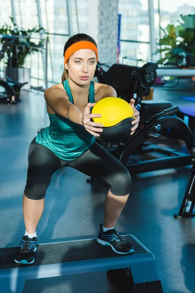 sporty woman training with medicine ball at gym