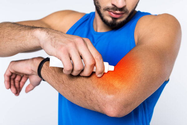 cropped shot of man applying ointment on arm while having arm pain