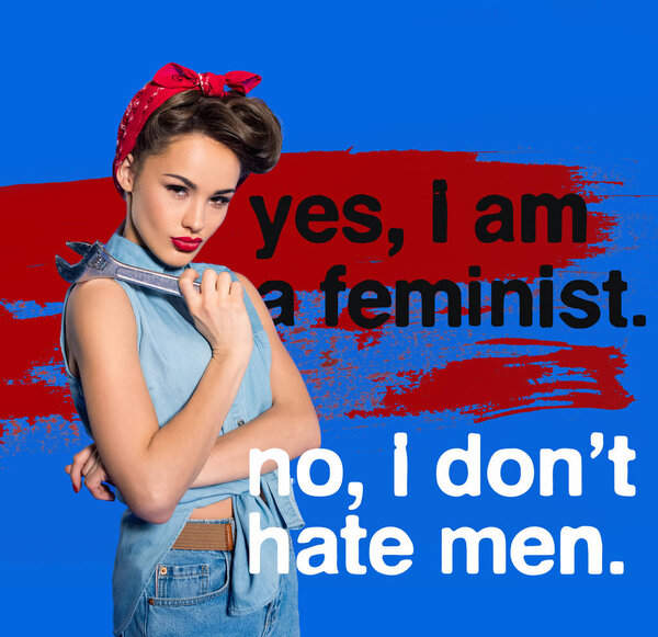 fashionable young woman in pin up style clothing with wrench and feminism quote