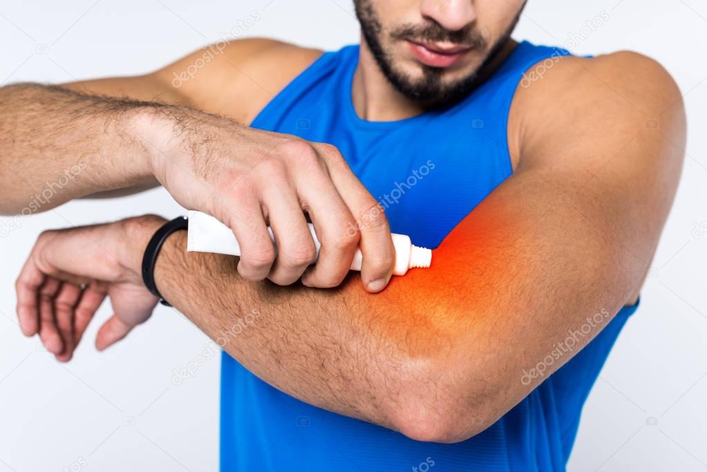 cropped shot of man applying ointment on arm while having arm pain