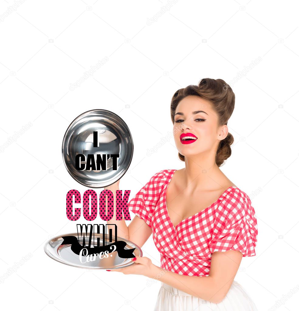 beautiful young woman in retro clothing with I CAN`T COOK, WHO CARES? lettering on serving tray in hands isolated on white