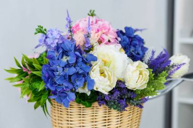 close up view of beautiful springtime bouquet of flowers in straw basket clipart