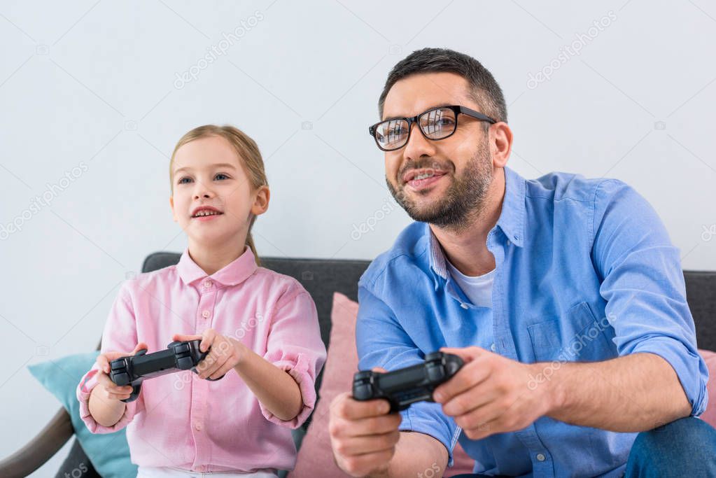 portrait of daughter and father playing video game together at home