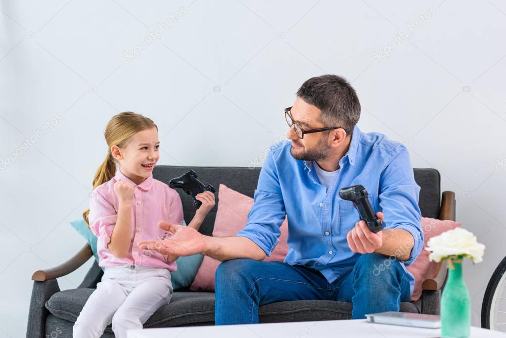 kid celebrating success while playing video game together with father at home
