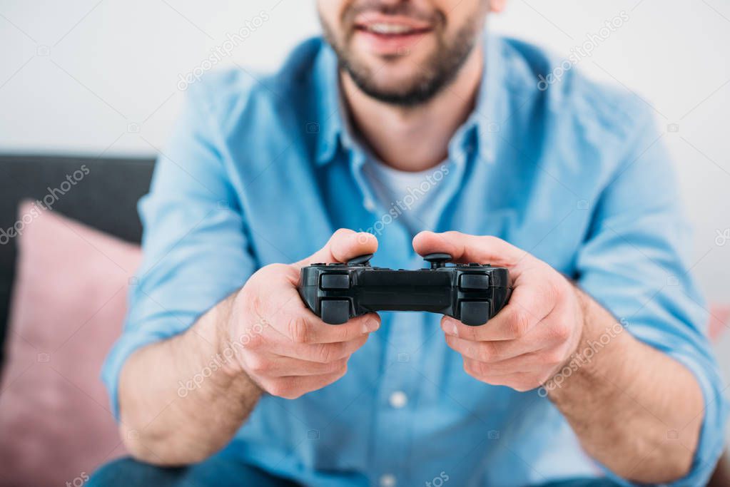 partial view of man playing video game at home