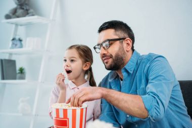 Baba ve kızı tv birlikte evde izlerken patlamış mısır yemek