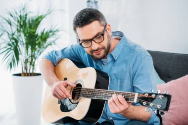 akustik gitar evde oynarken gözlük adam portresi