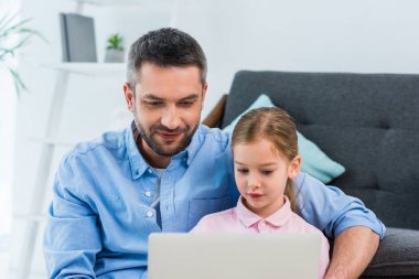 Baba ve kızı evde birlikte dizüstü kullanarak portre