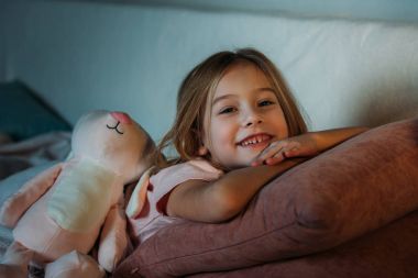 portrait of smiling kid with toy lying on sofa clipart