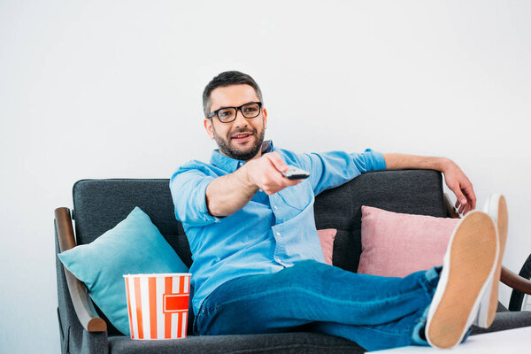 man in eyeglasses resting on sofa and watching tv at home