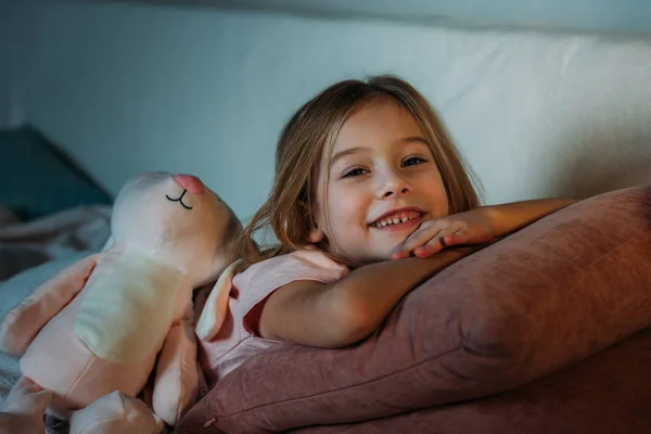 Portret Uśmiechający Się Dziecka Zabawkami Leżąc Kanapie — Zdjęcie stockowe