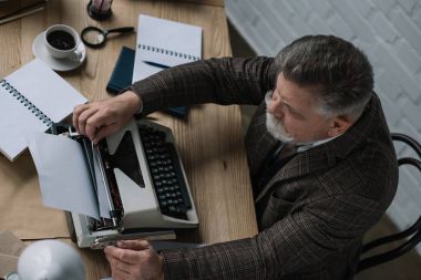 yüksek açılı görünüş kıdemli yazar daktilo kağıt yükleme